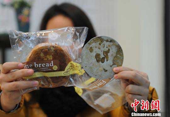 重慶市民向小姐一手拿著“紅豆密斯面包”，一手拿著從該品種面包中吃出的“鐵片” 。曹多然 攝